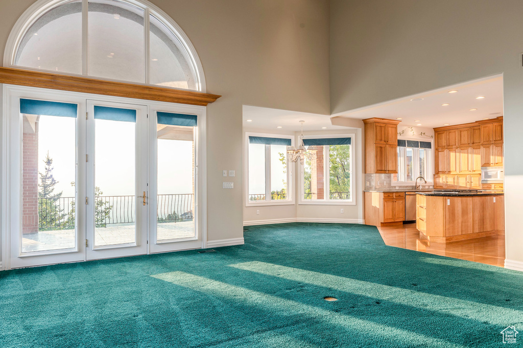 Unfurnished living room with light carpet, a wealth of natural light, and a high ceiling