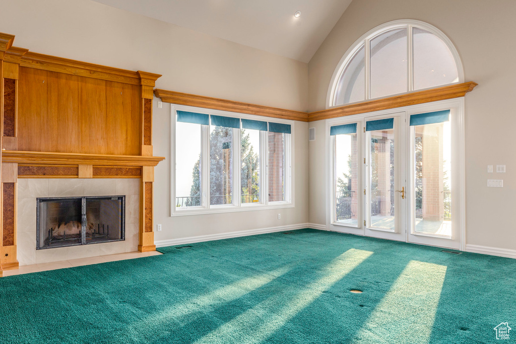 Unfurnished living room featuring french doors, a wealth of natural light, a fireplace, and carpet floors