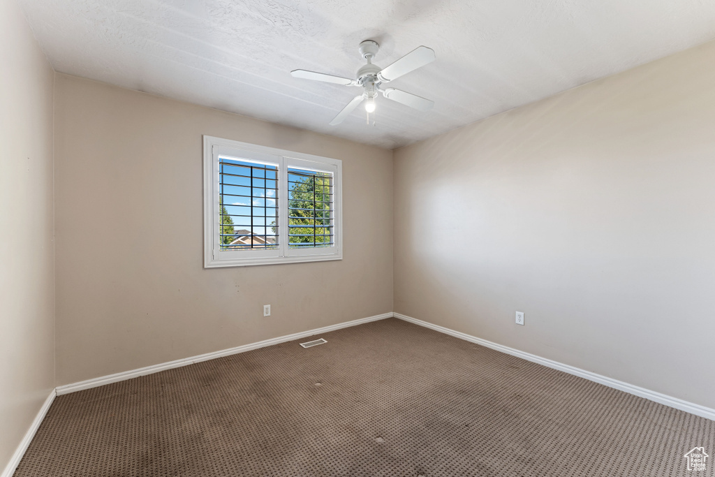 Unfurnished room featuring carpet floors and ceiling fan