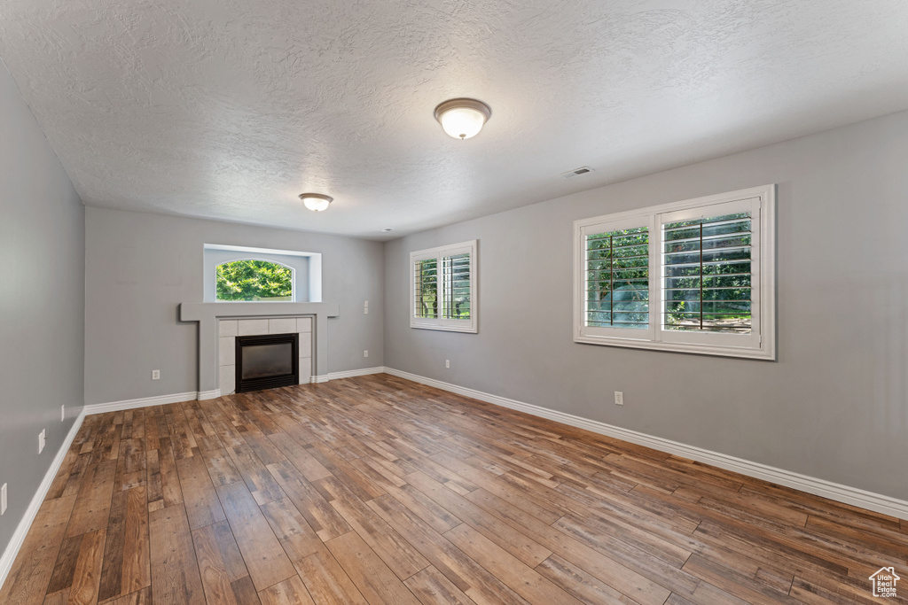 Unfurnished living room featuring a textured ceiling, a fireplace, and hardwood / wood-style floors