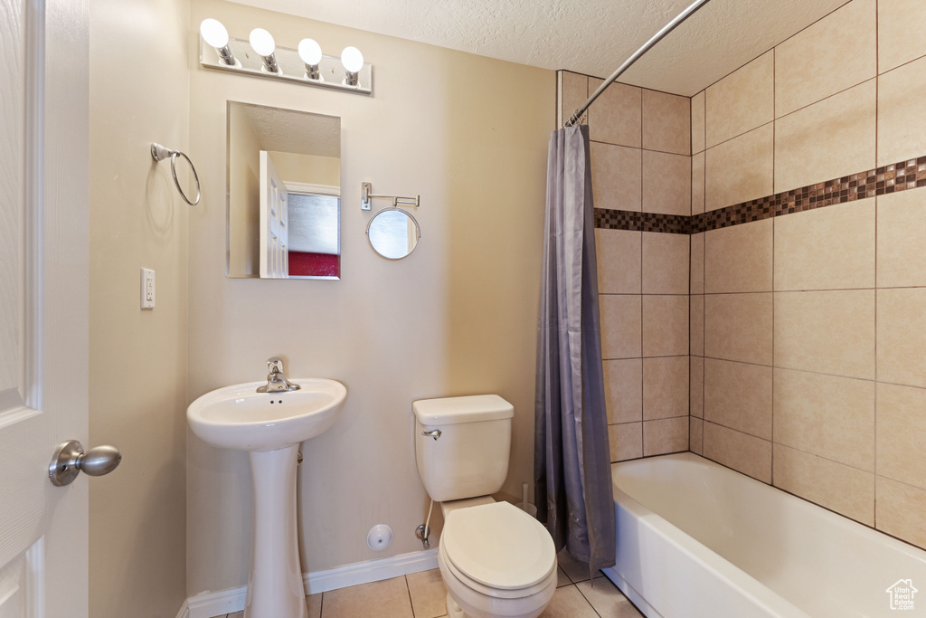 Bathroom with tile patterned floors, shower / bath combo, a textured ceiling, and toilet