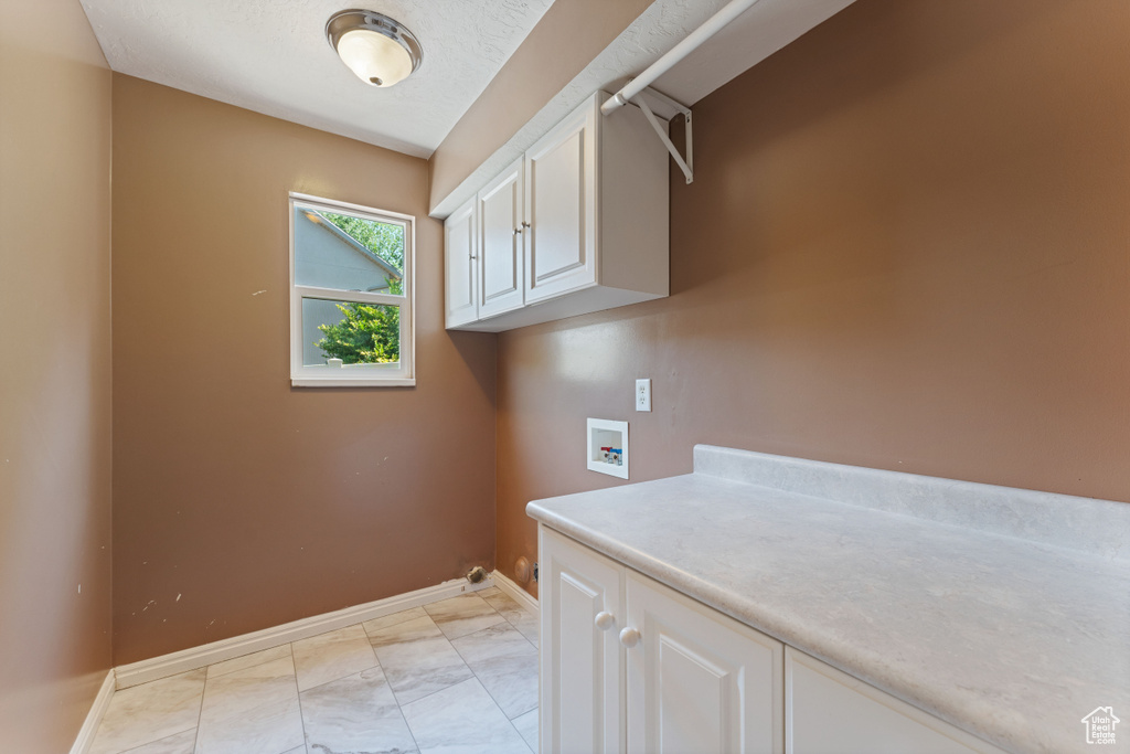 Laundry room with cabinets, washer hookup, and light tile patterned flooring