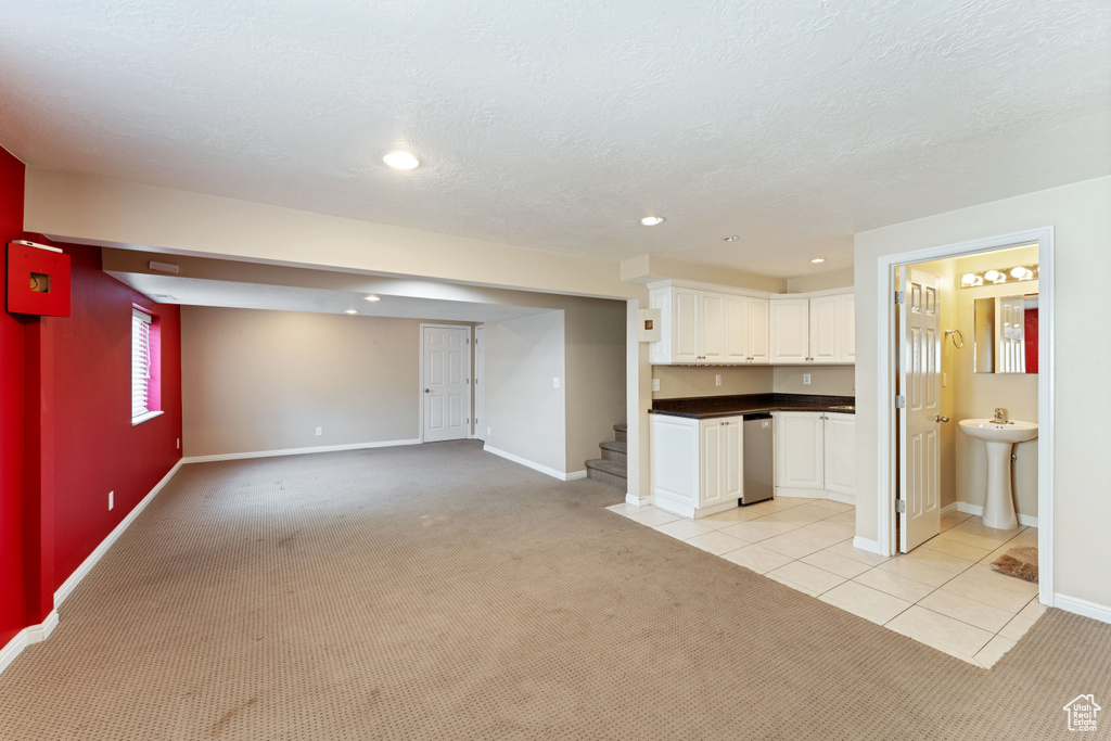 Unfurnished living room featuring sink and light colored carpet