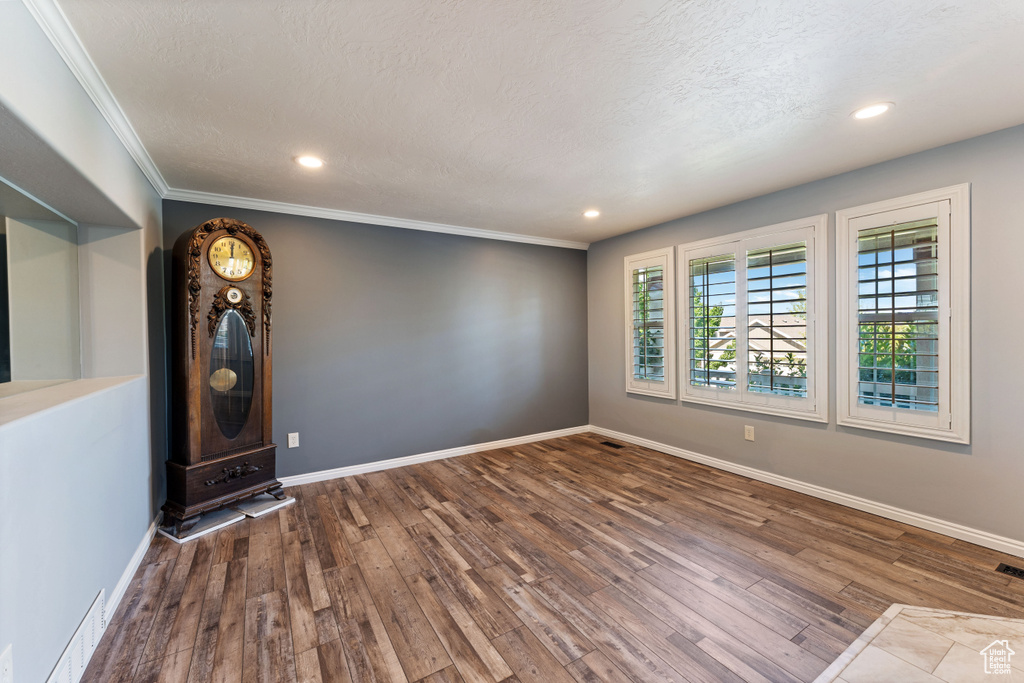 Unfurnished room featuring crown molding, hardwood / wood-style floors, and a textured ceiling