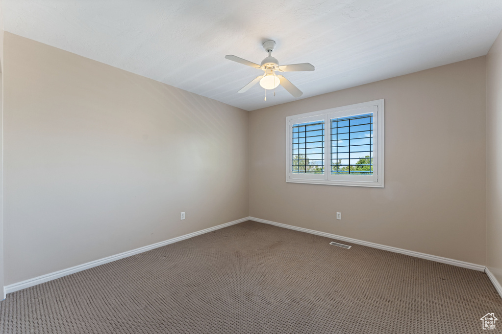 Empty room featuring carpet floors and ceiling fan