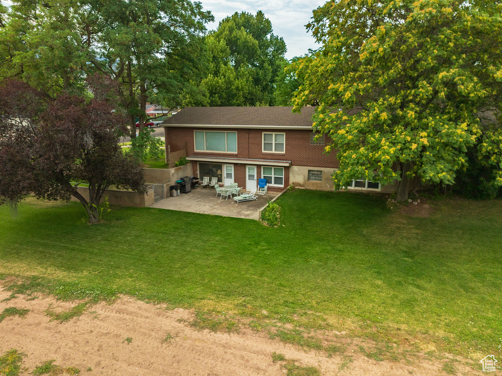 Rear view of house with a patio area and a yard