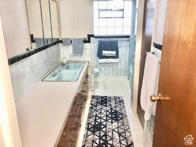 Bathroom with tile walls, backsplash, toilet, tile patterned floors, and dual bowl vanity