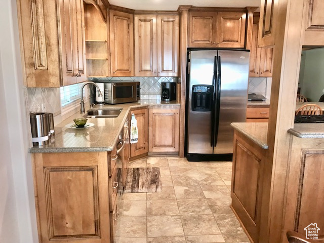 Kitchen with stainless steel appliances, backsplash, light tile patterned floors, and stone countertops