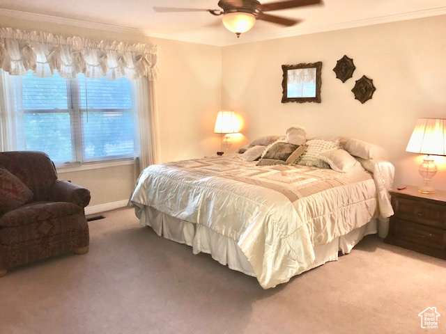 Carpeted bedroom featuring ornamental molding and ceiling fan