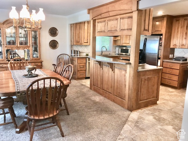 Kitchen featuring decorative backsplash, a notable chandelier, appliances with stainless steel finishes, and sink