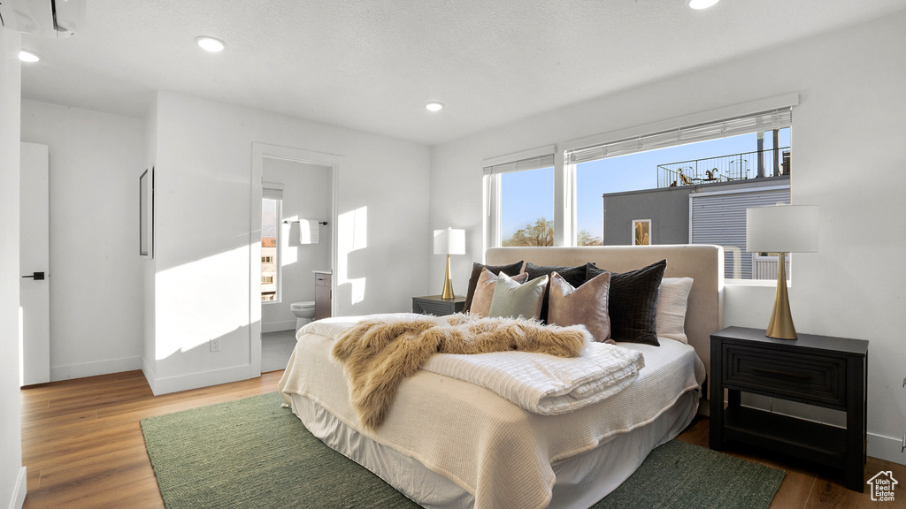 Bedroom with light hardwood / wood-style floors and ensuite bath