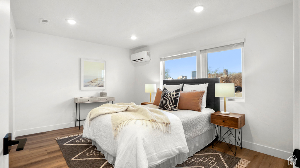 Bedroom with a wall unit AC and wood-type flooring