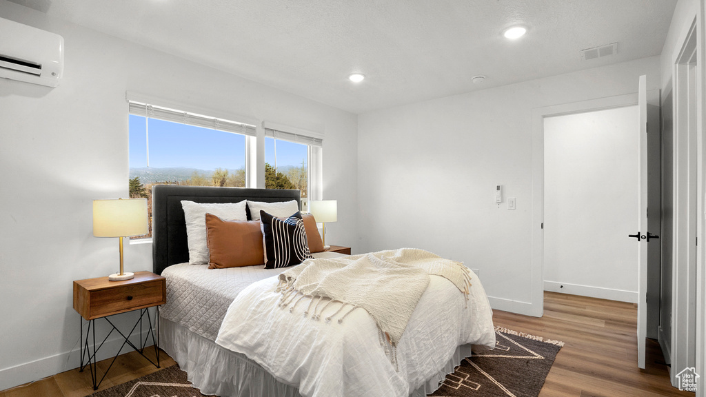 Bedroom featuring an AC wall unit and wood-type flooring