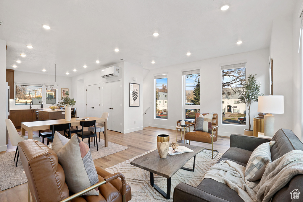 Living room featuring an AC wall unit, a wealth of natural light, and light wood-type flooring