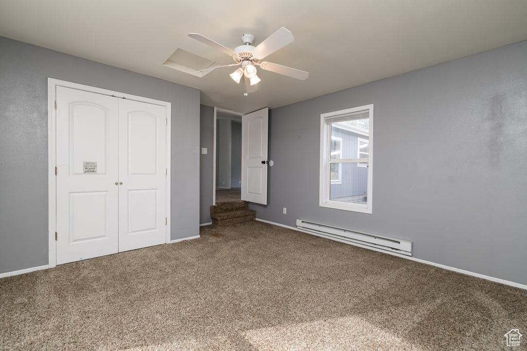Unfurnished bedroom featuring a baseboard heating unit, carpet, and ceiling fan