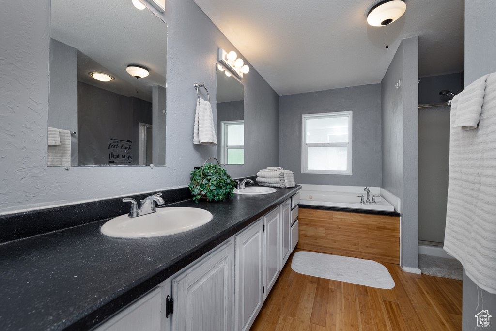 Bathroom with plus walk in shower, hardwood / wood-style floors, a textured ceiling, and vanity