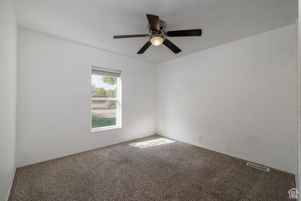 Carpeted empty room featuring ceiling fan