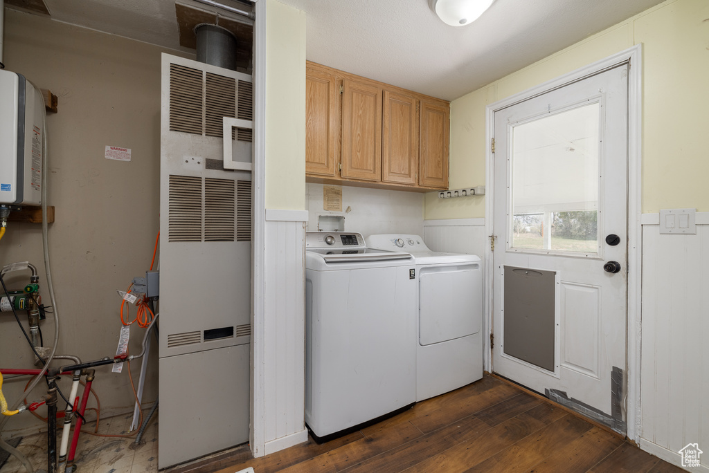 Washroom with cabinets, separate washer and dryer, tankless water heater, and dark hardwood / wood-style flooring