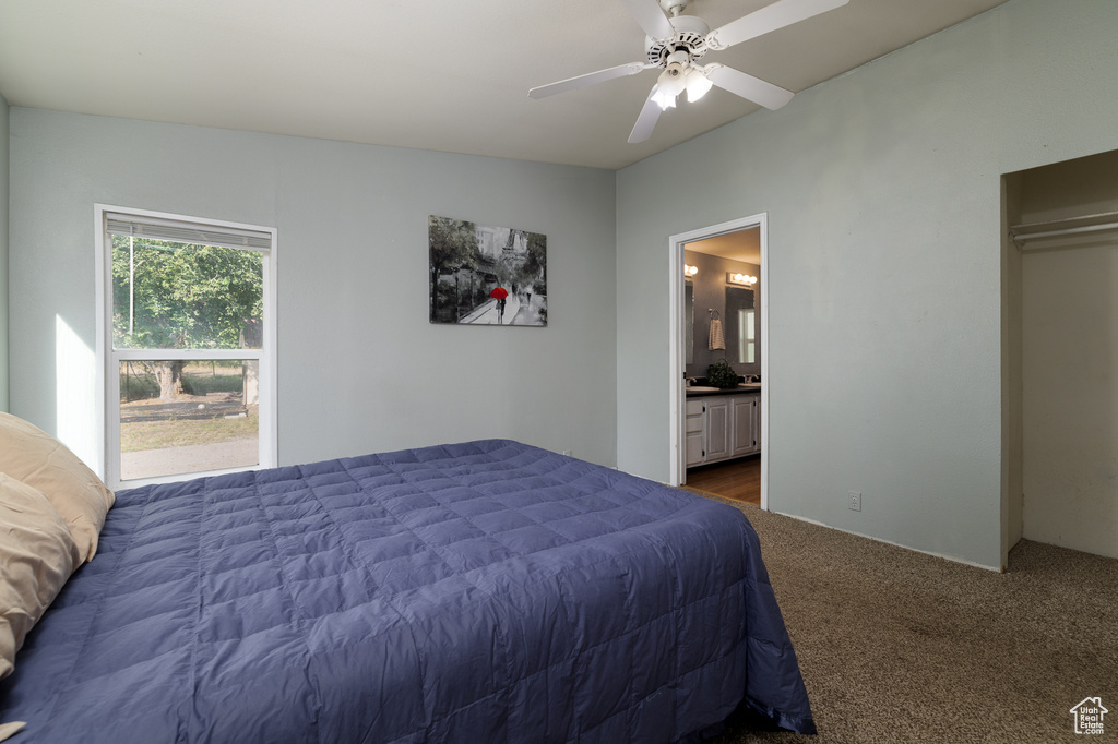 Bedroom with lofted ceiling, connected bathroom, ceiling fan, and carpet flooring
