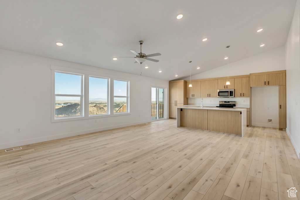 Kitchen featuring appliances with stainless steel finishes, light wood-type flooring, an island with sink, vaulted ceiling, and pendant lighting