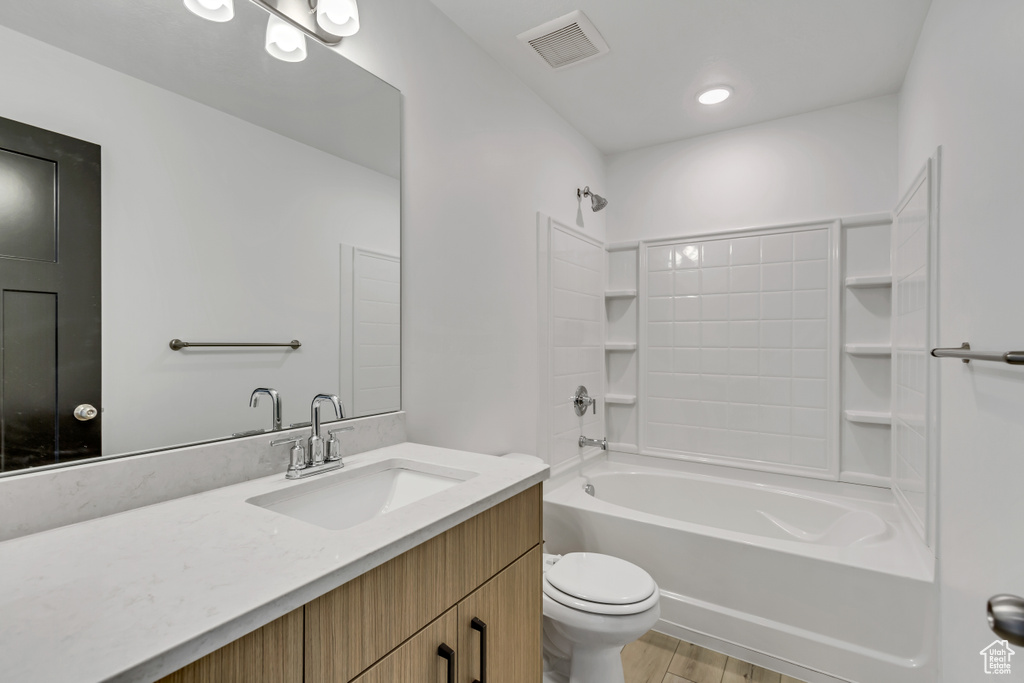 Full bathroom with toilet, vanity, wood-type flooring, and shower / bathtub combination