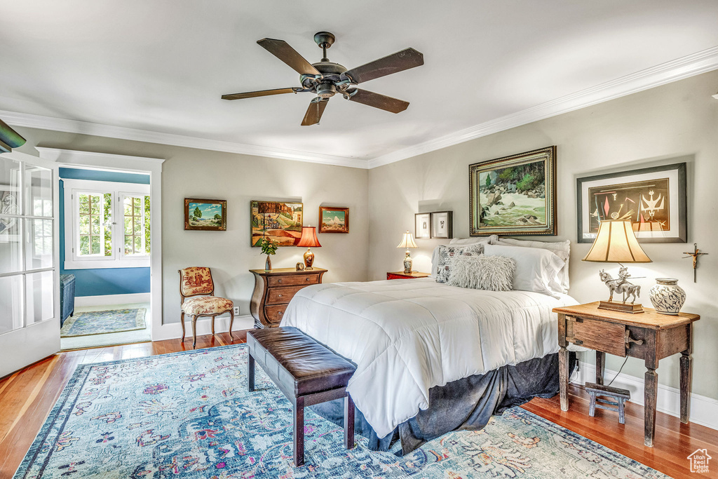 Bedroom featuring hardwood / wood-style flooring, ornamental molding, and ceiling fan