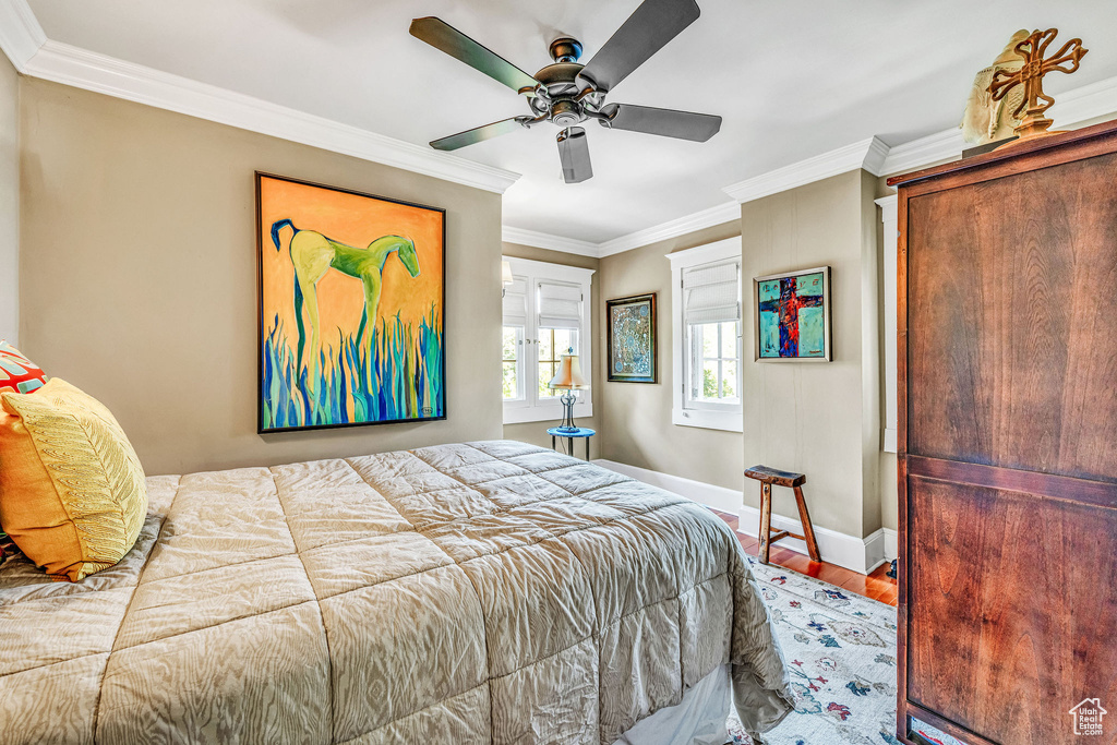 Bedroom with ornamental molding, hardwood / wood-style flooring, and ceiling fan