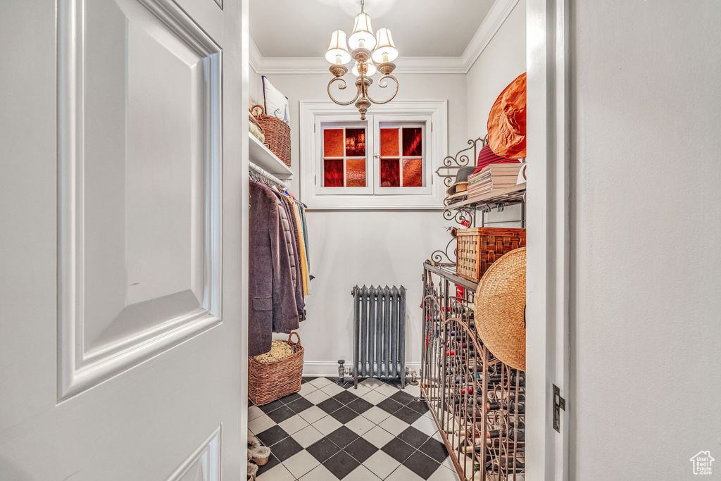 Walk in closet with tile patterned floors, a chandelier, and radiator