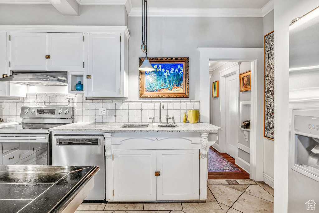 Kitchen featuring light tile patterned flooring, pendant lighting, decorative backsplash, and appliances with stainless steel finishes