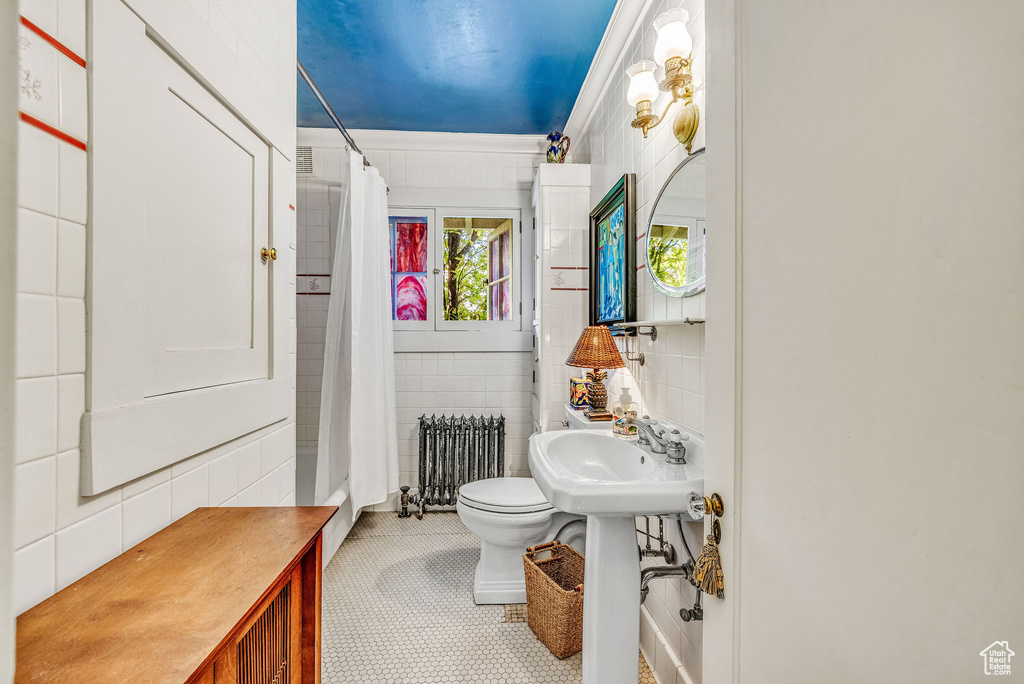Bathroom featuring tile walls, radiator heating unit, decorative backsplash, toilet, and tile patterned flooring