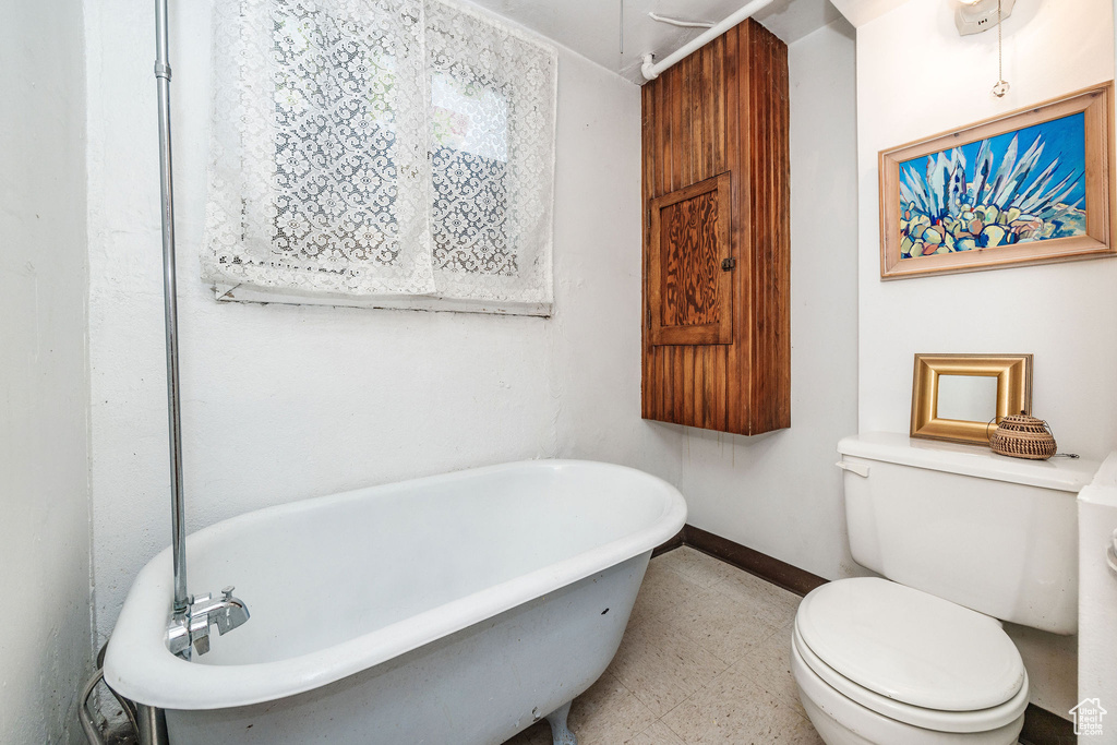 Bathroom featuring toilet, tile patterned flooring, and a bathtub