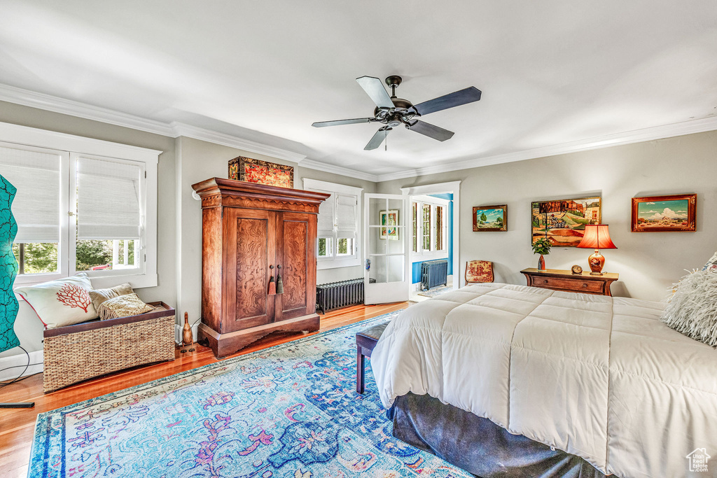 Bedroom with radiator heating unit, light hardwood / wood-style flooring, ceiling fan, and crown molding