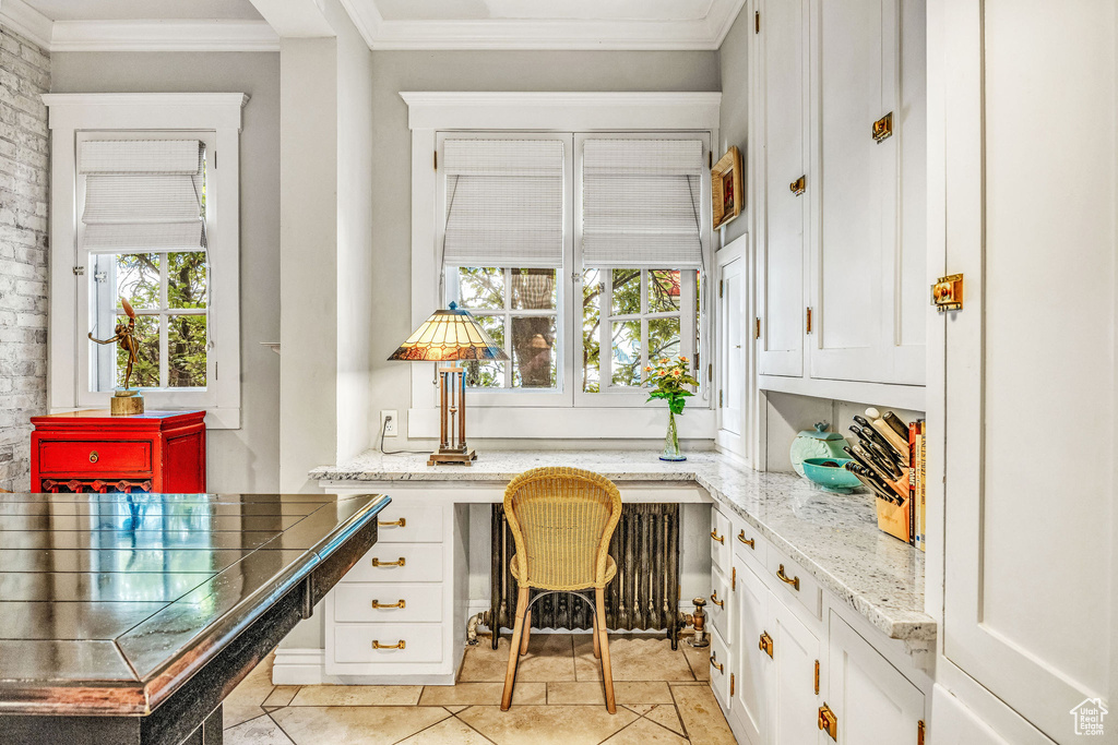 Tiled home office featuring plenty of natural light, crown molding, and built in desk