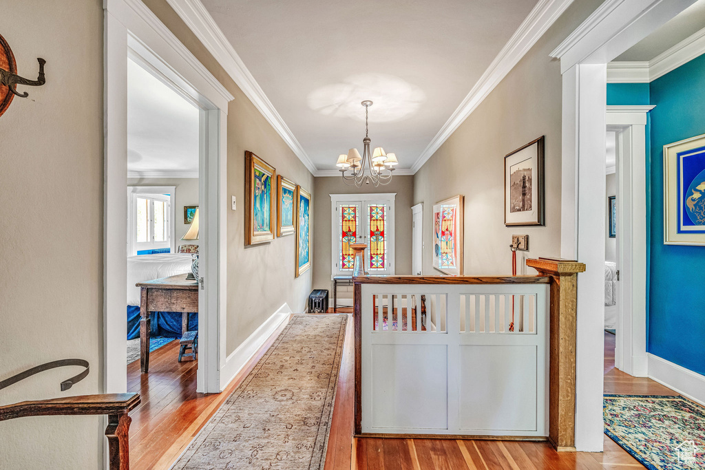 Hallway featuring light hardwood / wood-style floors, crown molding, and a chandelier