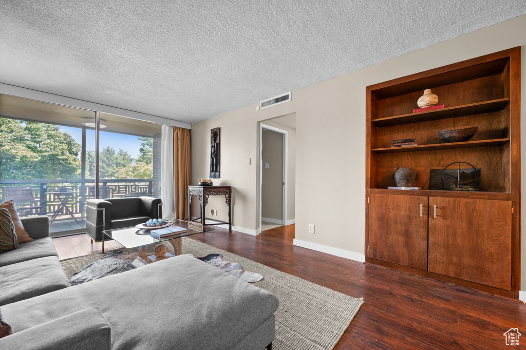 Living room featuring built in features, dark hardwood / wood-style floors, and a textured ceiling