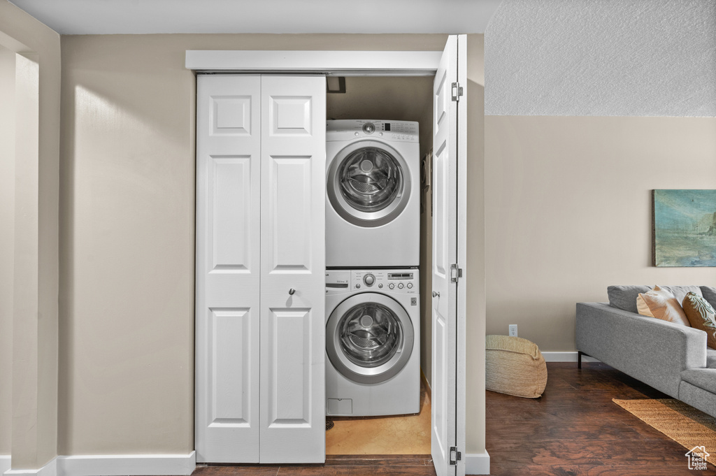 Laundry room with dark hardwood / wood-style floors and stacked washer / dryer