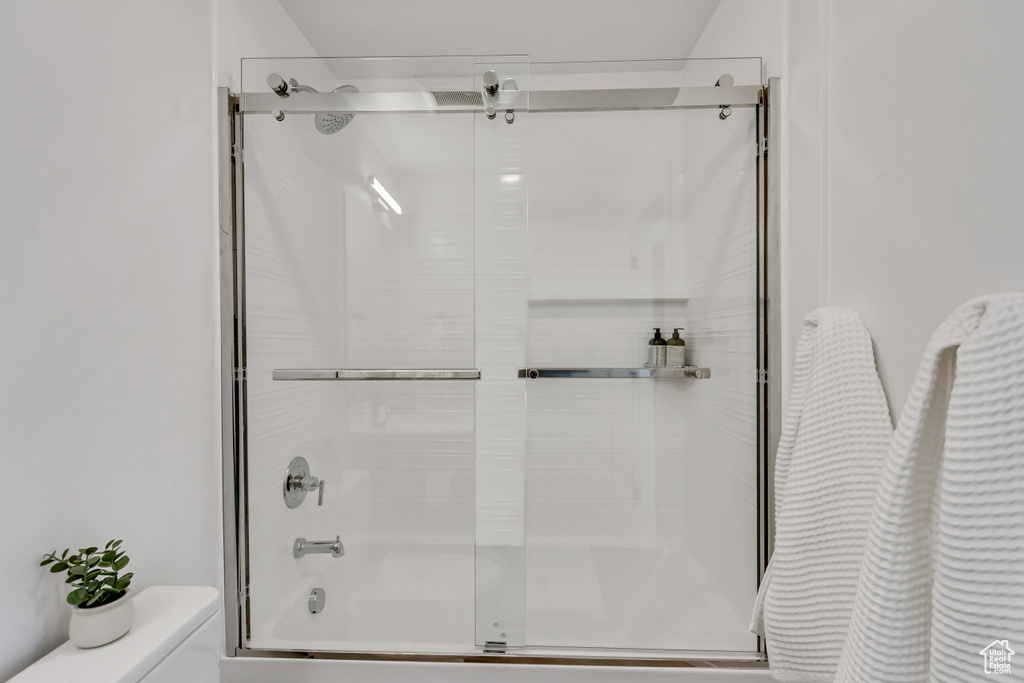 Bathroom with toilet and shower / bath combination with glass door