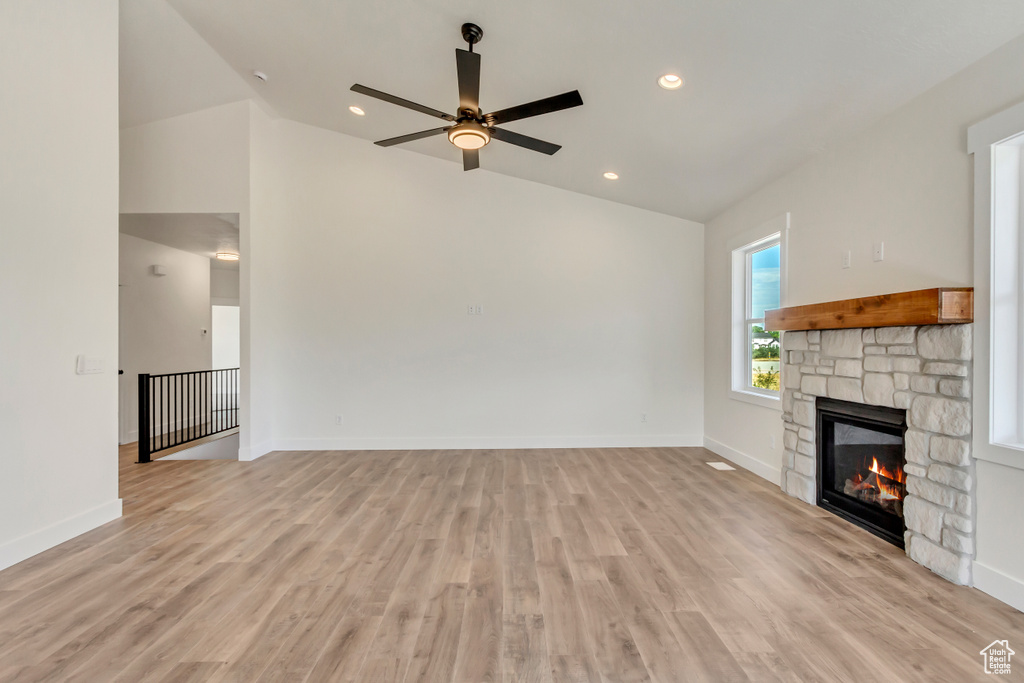 Unfurnished living room featuring light hardwood / wood-style flooring, ceiling fan, and lofted ceiling