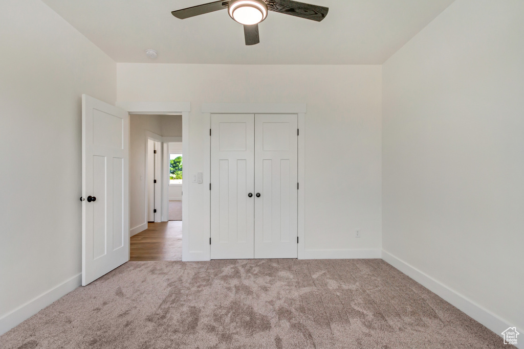 Unfurnished bedroom with light carpet, a closet, and ceiling fan