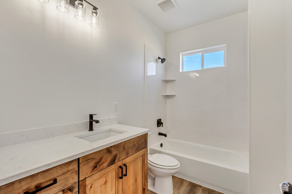 Full bathroom with vanity, toilet, wood-type flooring, and shower / washtub combination