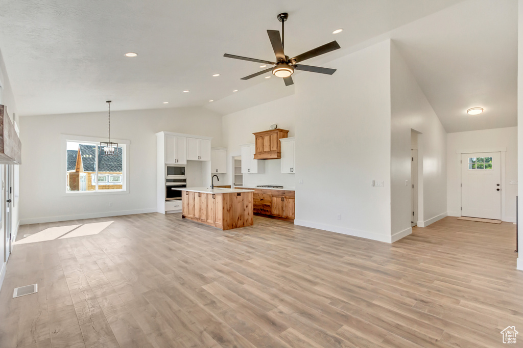 Kitchen featuring white microwave, oven, light hardwood / wood-style flooring, and a center island with sink