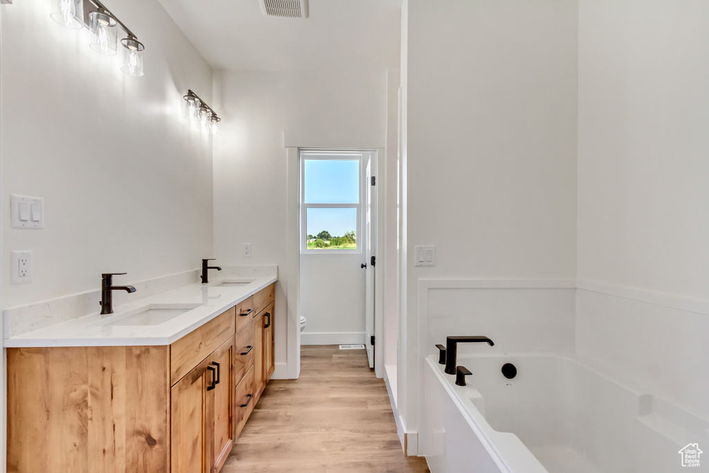 Bathroom with toilet, a bathing tub, hardwood / wood-style floors, and dual bowl vanity