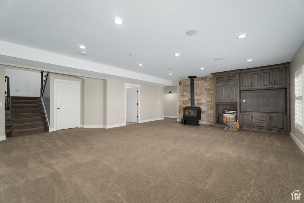 Unfurnished living room with a wood stove and carpet floors