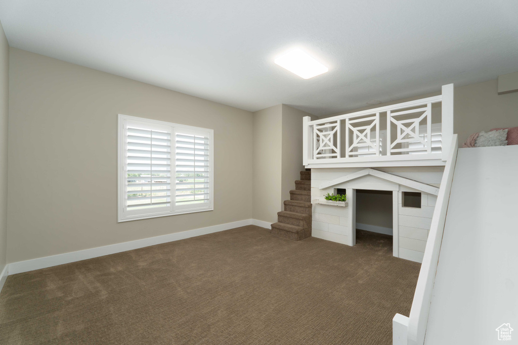 Unfurnished bedroom featuring built in desk and carpet floors