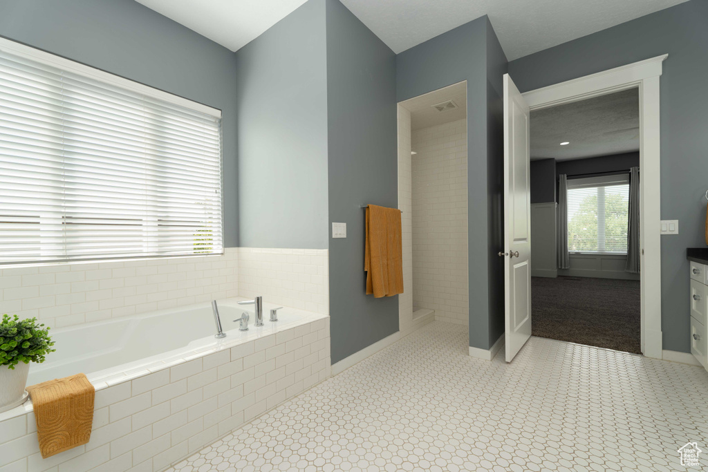 Bathroom with tile patterned flooring, tiled bath, and vanity