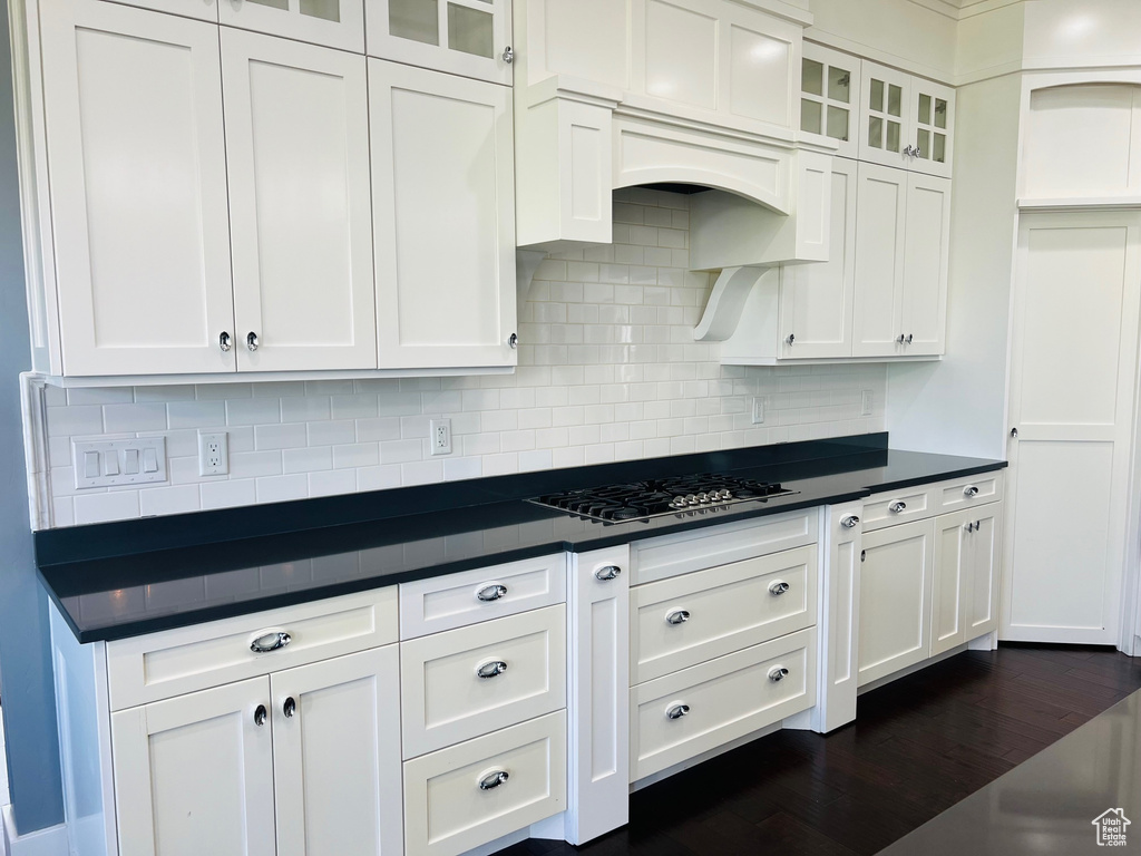 Kitchen featuring white cabinetry, dark wood-type flooring, and backsplash