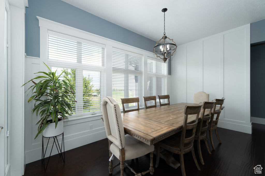 Dining space with dark wood-type flooring and an inviting chandelier