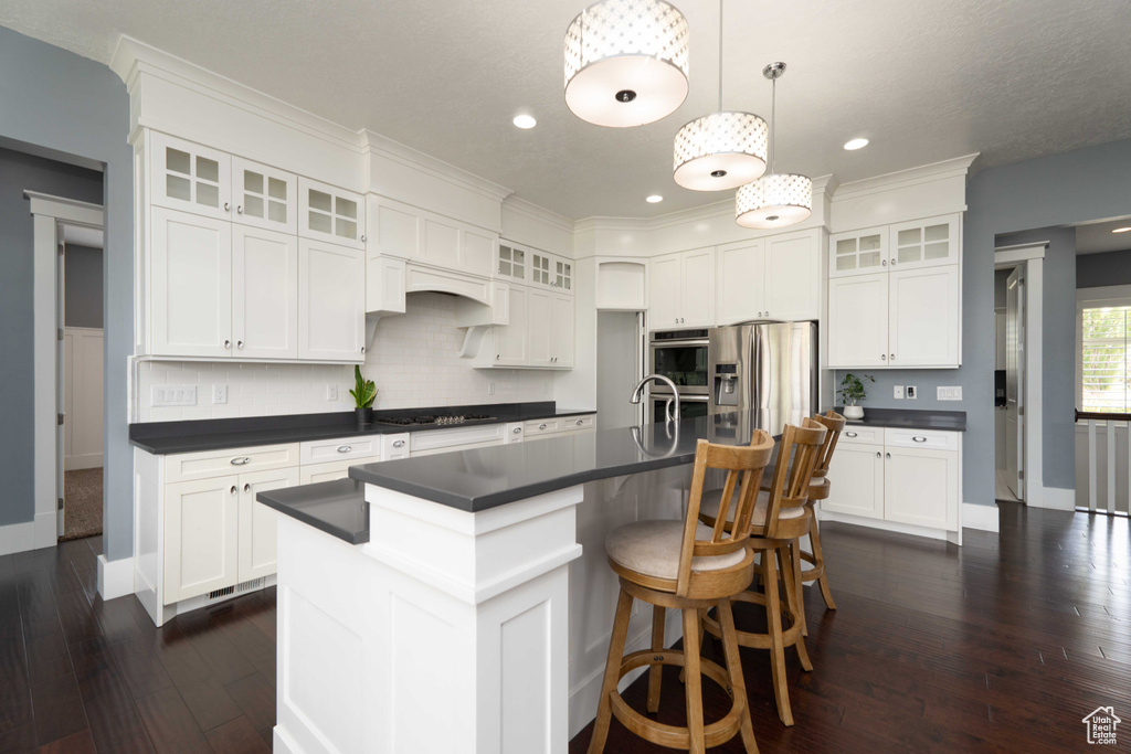 Kitchen featuring tasteful backsplash, stainless steel fridge with ice dispenser, dark hardwood / wood-style floors, an island with sink, and white cabinetry