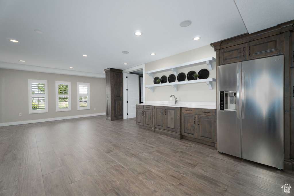 Kitchen featuring stainless steel fridge, sink, light wood-type flooring, and dark brown cabinetry