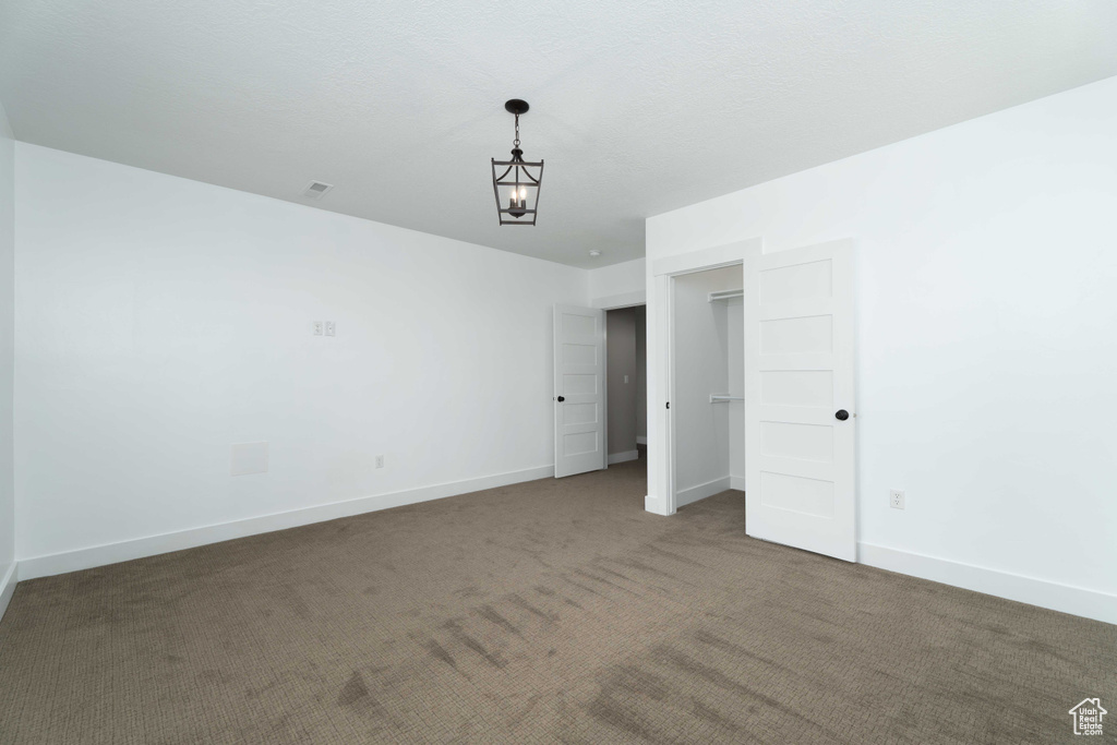 Unfurnished bedroom featuring carpet and a notable chandelier